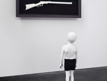 Boy stands in front of art gun