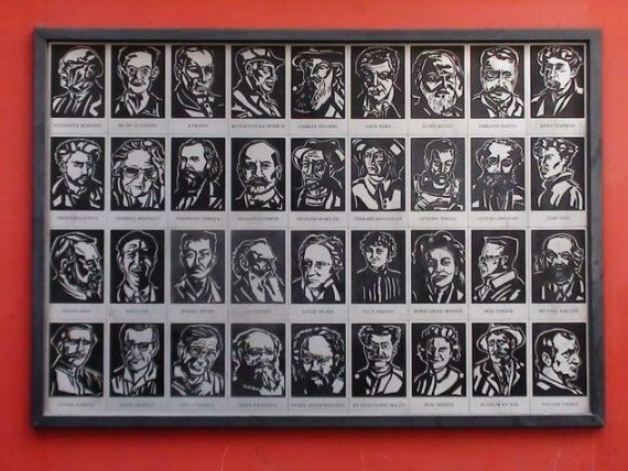 Photo of an artwork featuring 36 engraved portraits, mounted on a red wall