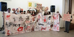 young people holding up a cotton sheet with graffiti on it