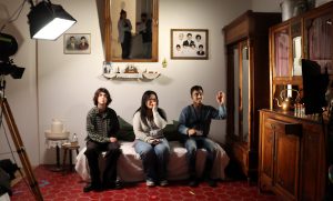 Three young people sit within a scene created by Zineb Sedira
