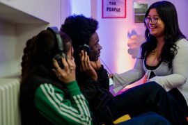 three young people with overhead headphones on chatting