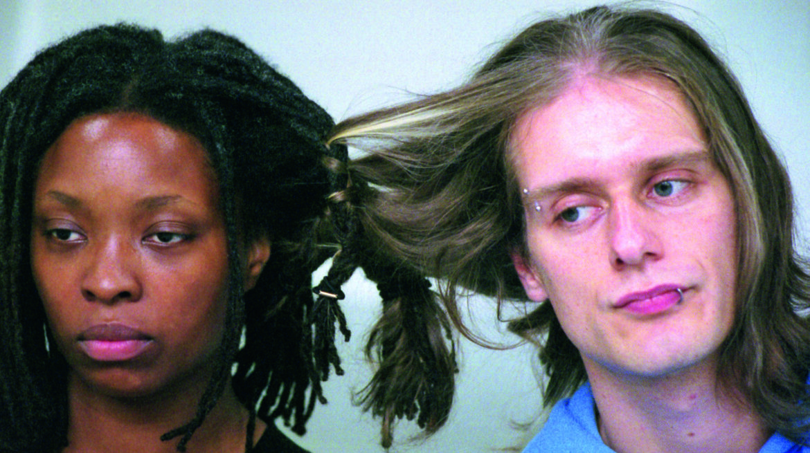 two figures, a black female and a white male, with their hair braided together