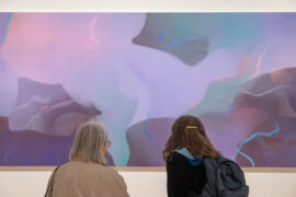 Two women looking at purple abstract landscape