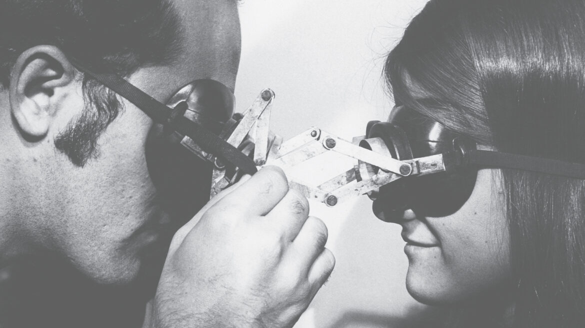 black and white image of two people looking at each other through goggles