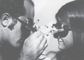 black and white image of two people looking at each other through goggles