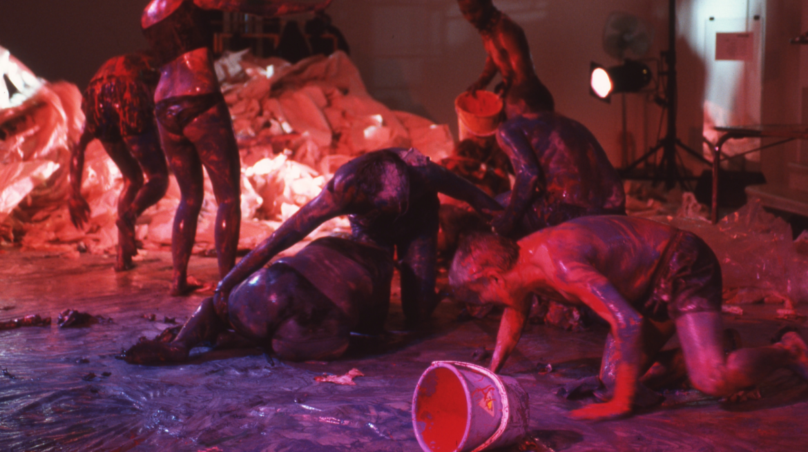 pink and purple image of performers smothering themselves with fluids