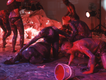 pink and purple image of performers smothering themselves with fluids