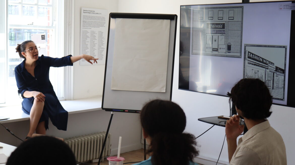 Young people look towards a screen which displays drawings, an artist points towards it