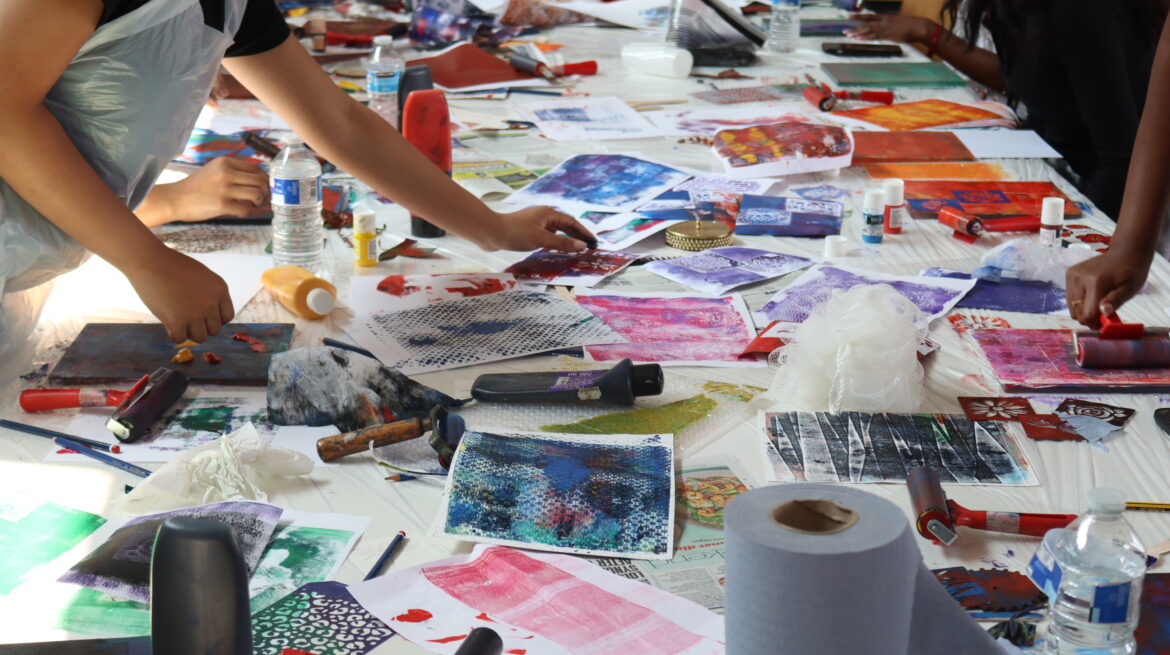 Table covered in paint and pieces of paper with colourful prints